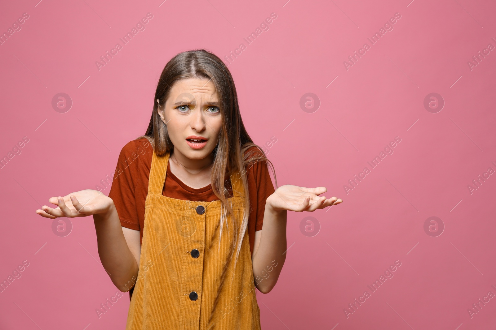 Photo of Confused teenage girl on pink background. Space for text