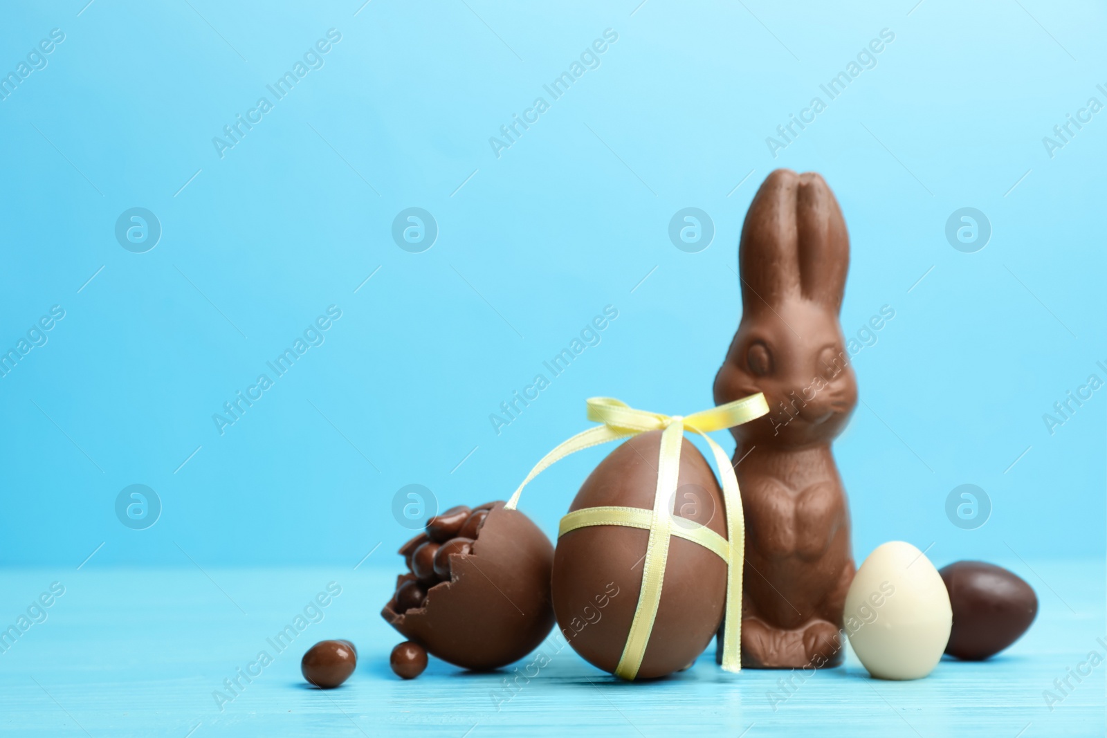 Photo of Composition with chocolate Easter eggs and bunny on table. Space for text