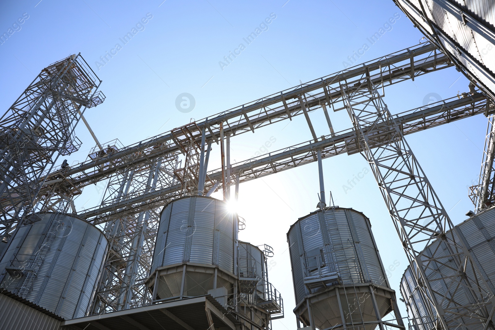 Photo of Modern granaries for storing cereal grains against blue sky, low angle view