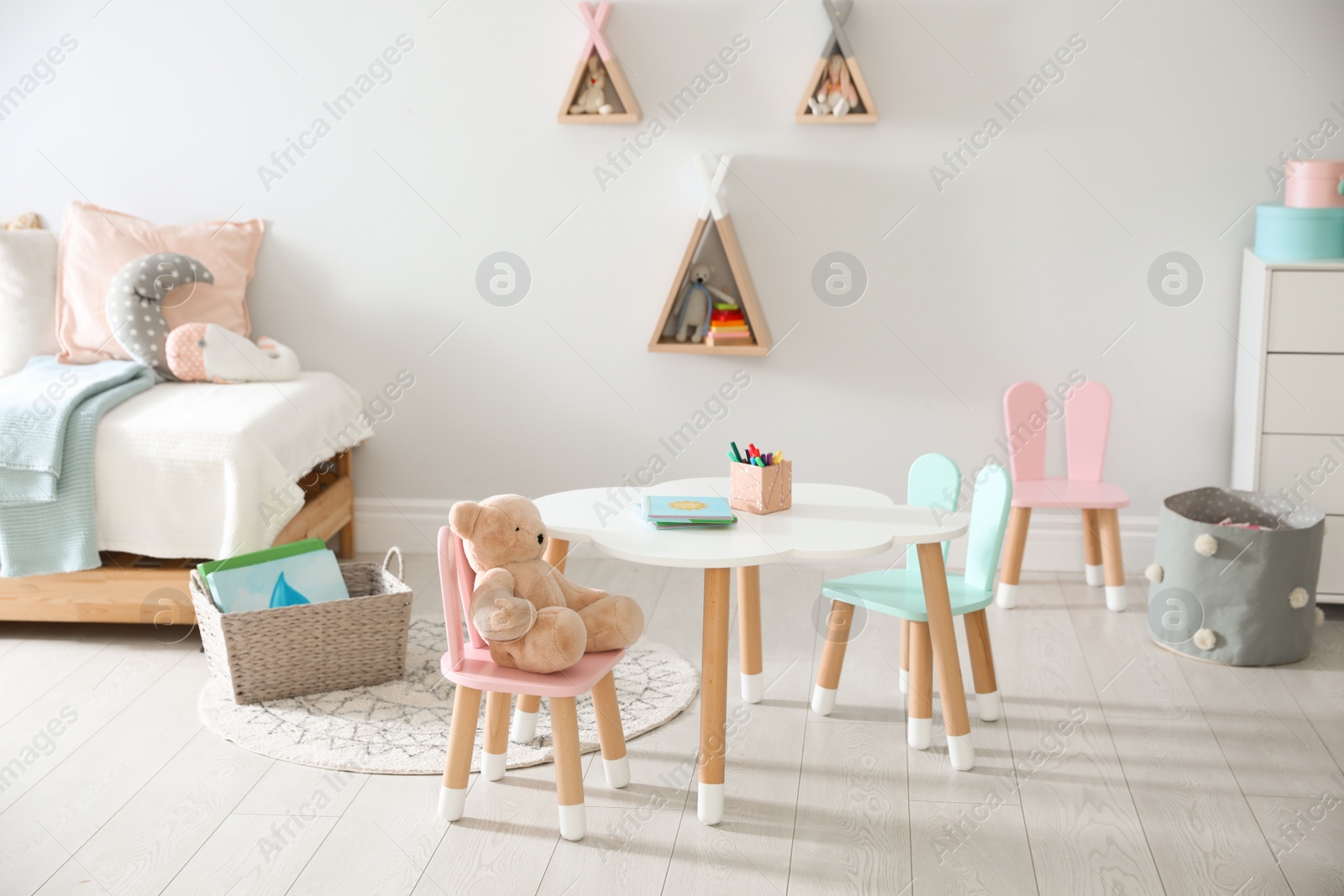 Photo of Small table and chairs with bunny ears in children's room interior