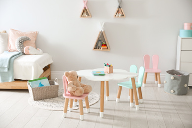 Small table and chairs with bunny ears in children's room interior