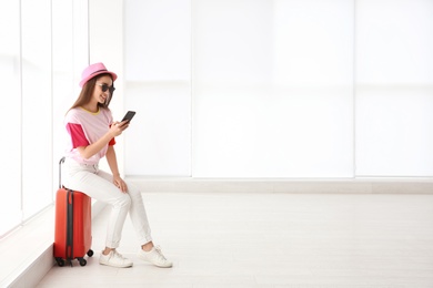 Photo of Young woman sitting on suitcase in airport