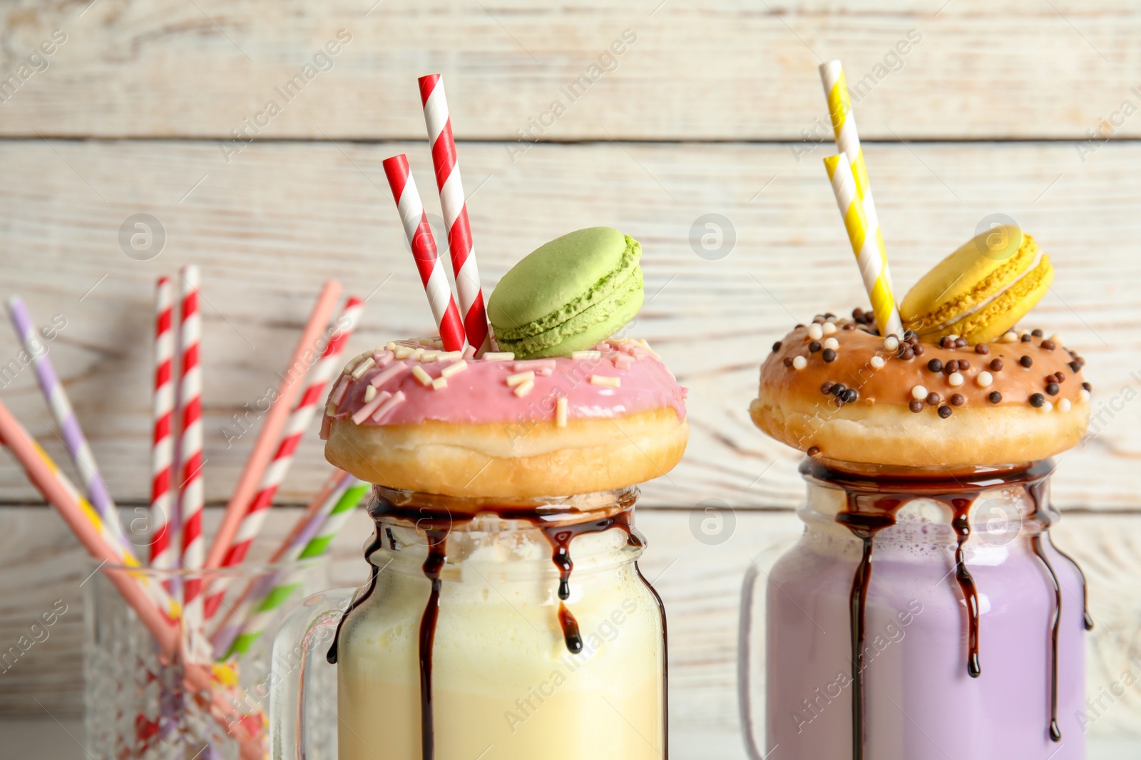 Photo of Mason jars with delicious milk shakes on light background, closeup