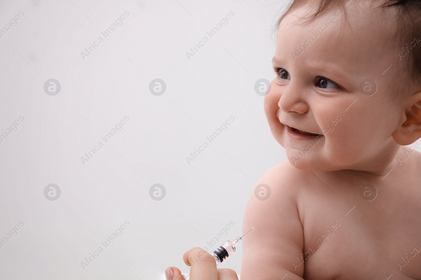 Photo of Doctor vaccinating baby against light background. Health care