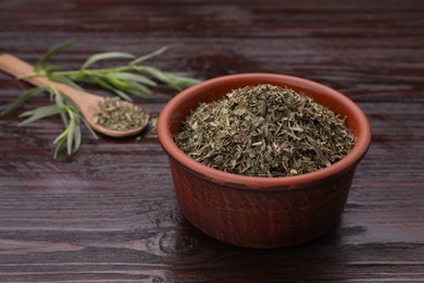 Photo of Dry tarragon in bowl on wooden table, space for text