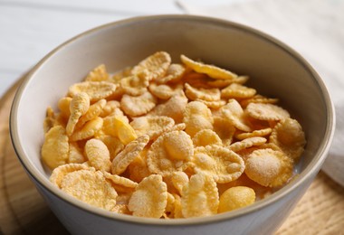 Photo of Tasty cornflakes with milk in bowl on table, closeup