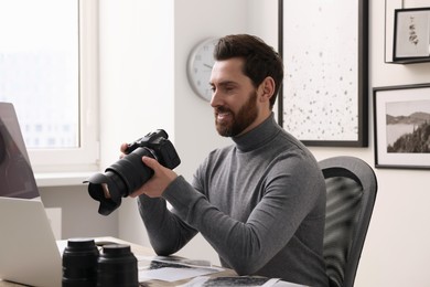 Photo of Professional photographer with digital camera at table in office