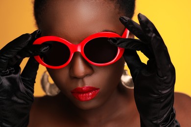 Photo of Fashionable portraitbeautiful woman with stylish sunglasses on yellow background, closeup