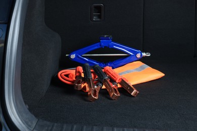 Photo of Scissor jack, life vest and battery jumper cables in trunk. Car safety equipment