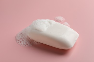 Photo of Soap with fluffy foam on pink background
