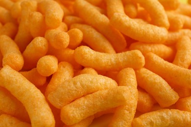 Tasty cheesy corn puffs as background, closeup