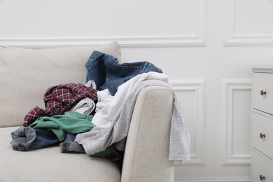 Photo of Pile of dirty clothes on sofa in living room