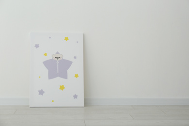 Photo of Adorable picture of animal and stars on floor near white wall, space for text. Children's room interior element
