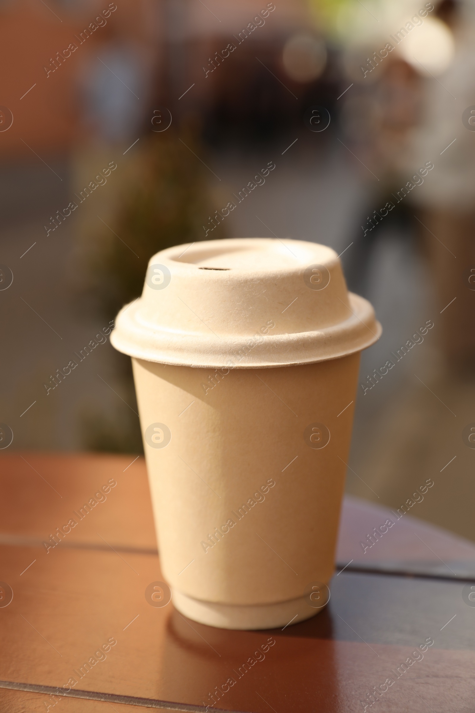 Photo of Cardboard takeaway coffee cup with lid on wooden table in city