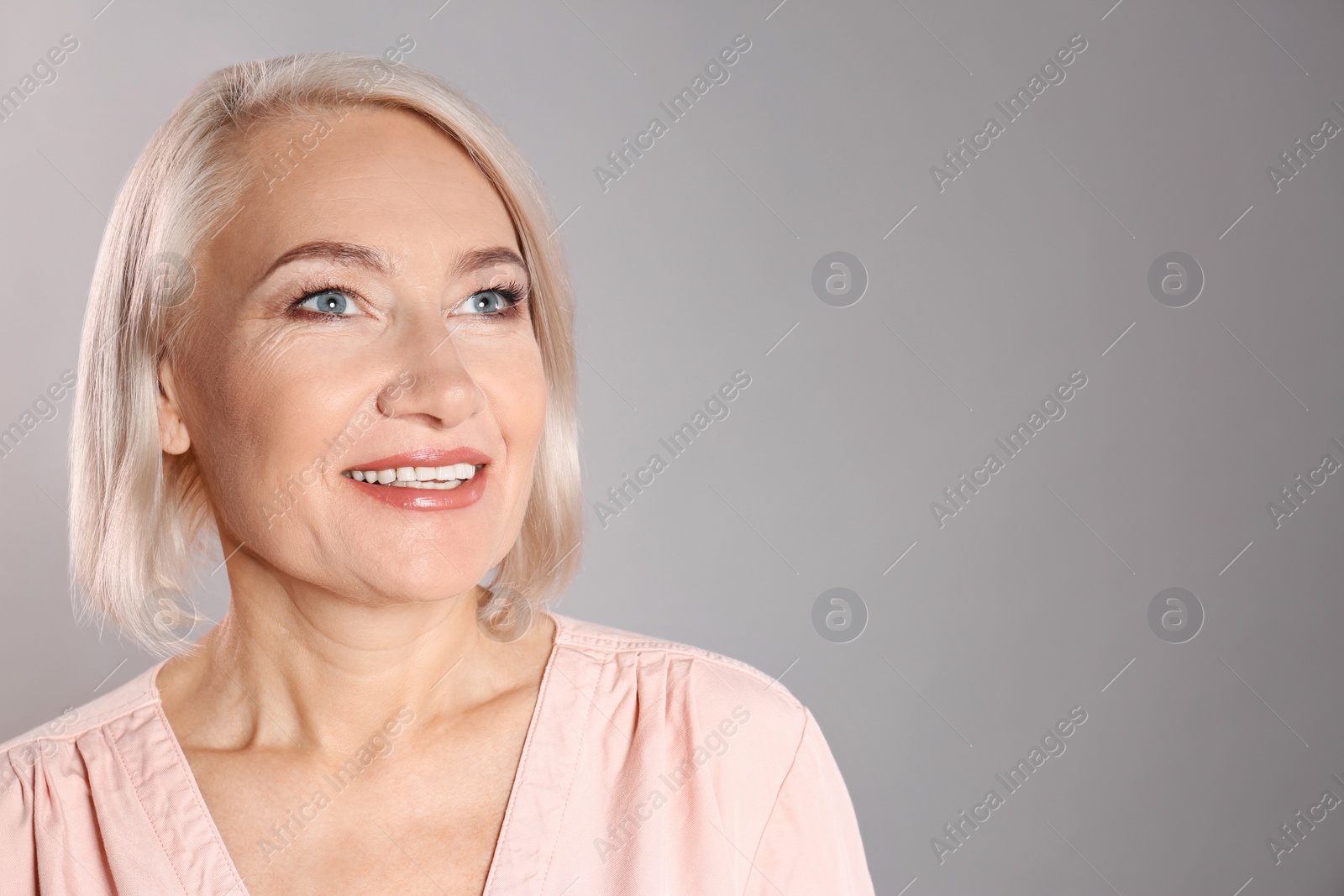 Photo of Portrait of charming mature woman with healthy beautiful face skin and natural makeup on grey background, space for text