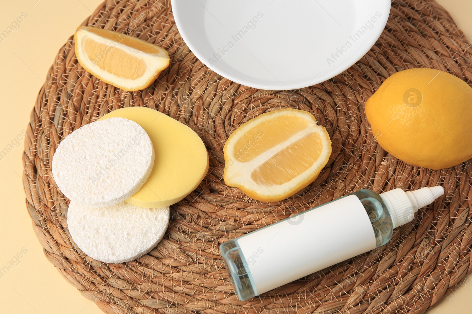 Photo of Lemon face cleanser. Fresh citrus fruits and personal care products on wicker mat, closeup