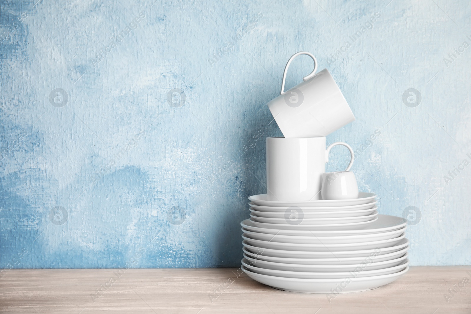 Photo of Set of dinnerware on table against color background with space for text. Interior element