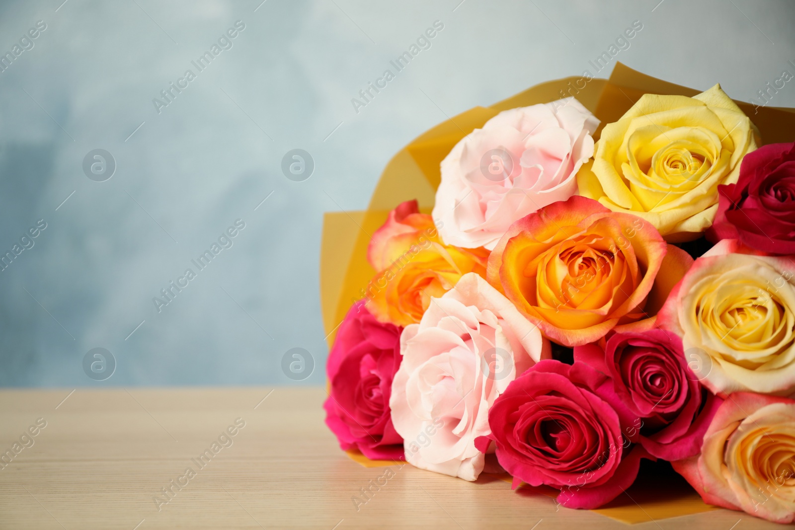 Photo of Luxury bouquet of fresh roses on wooden table, closeup. Space for text