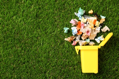 Trash bin and different garbage on green grass, top view with space for text. Waste recycling concept