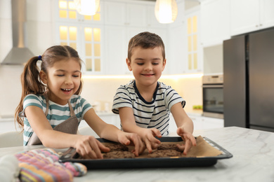 Photo of Cute little children with fresh delicious cookies in kitchen. Cooking together