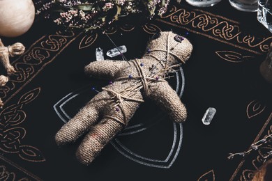 Image of Voodoo doll pierced with pins surrounded by ceremonial items on table. Curse ceremony