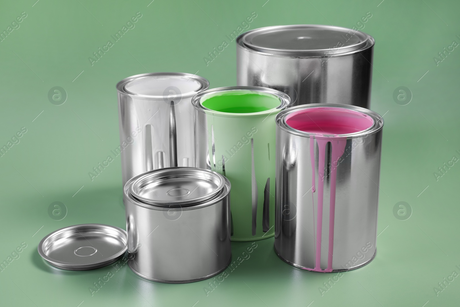 Photo of Cans of paints on light green background
