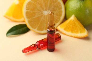 Skincare ampoules with vitamin C, different citrus fruits and leaves on beige background, closeup