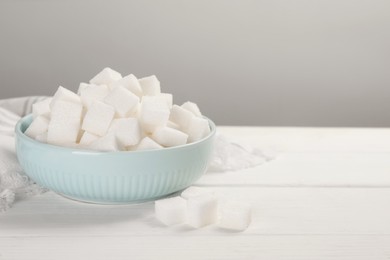 Photo of Bowl with sugar cubes on white table. Space for text