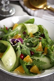 Photo of Delicious salad with cucumber and orange slices on gray table, closeup
