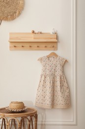 Photo of Wooden rack with cute dress in child room. Interior design