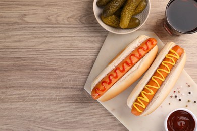 Photo of Tasty hot dogs with ketchup and mustard served on wooden table, flat lay