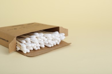 Photo of Box with wooden cotton buds on beige background. Space for text