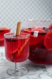 Photo of Glass and bowl of delicious aromatic punch drink on white marble table, closeup