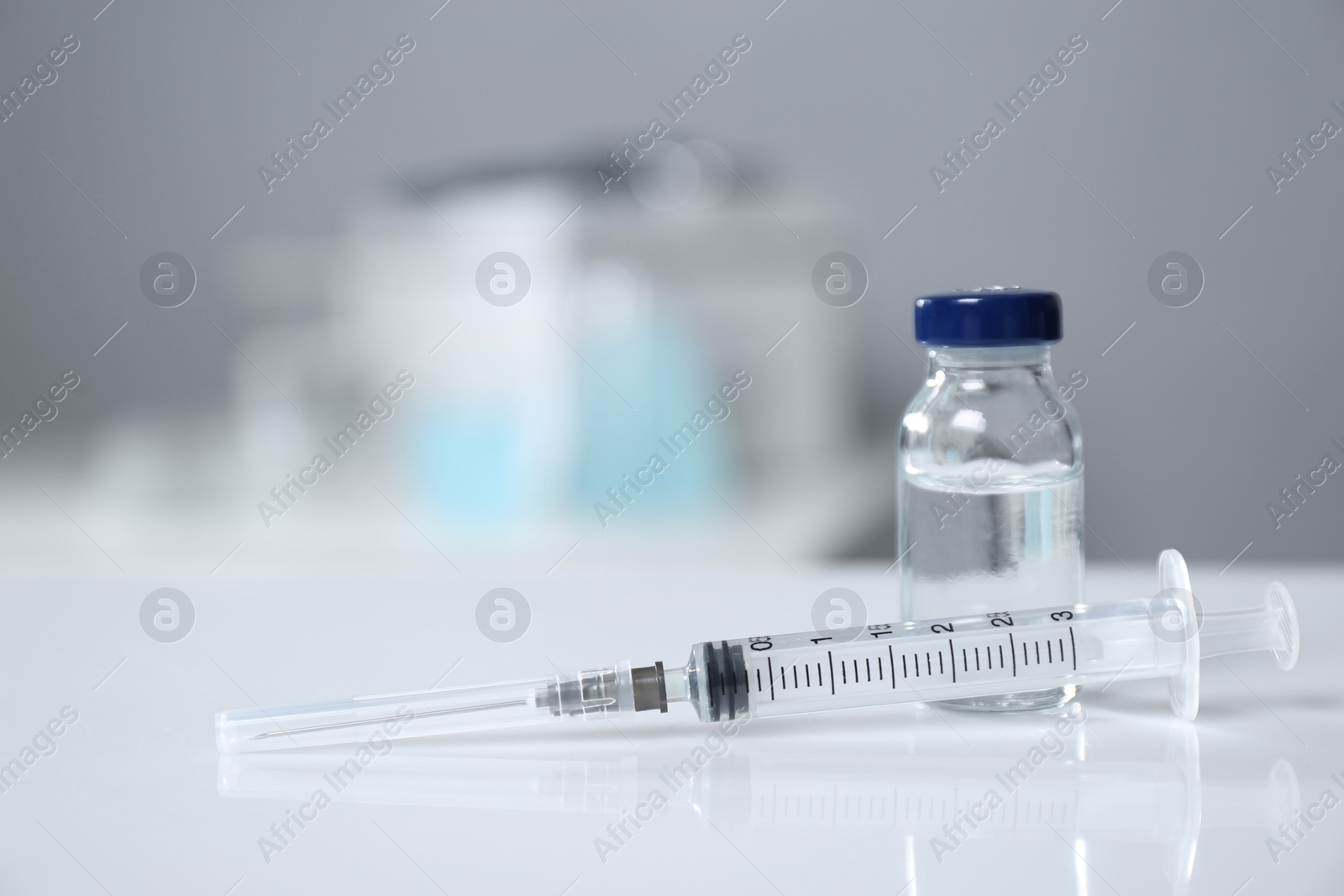 Photo of Syringe and vial on white table. Space for text