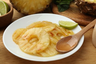 Tasty grilled pineapple slices and lime on wooden table, closeup