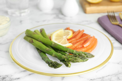 Photo of Tasty asparagus with salmon and lemon on white marble table