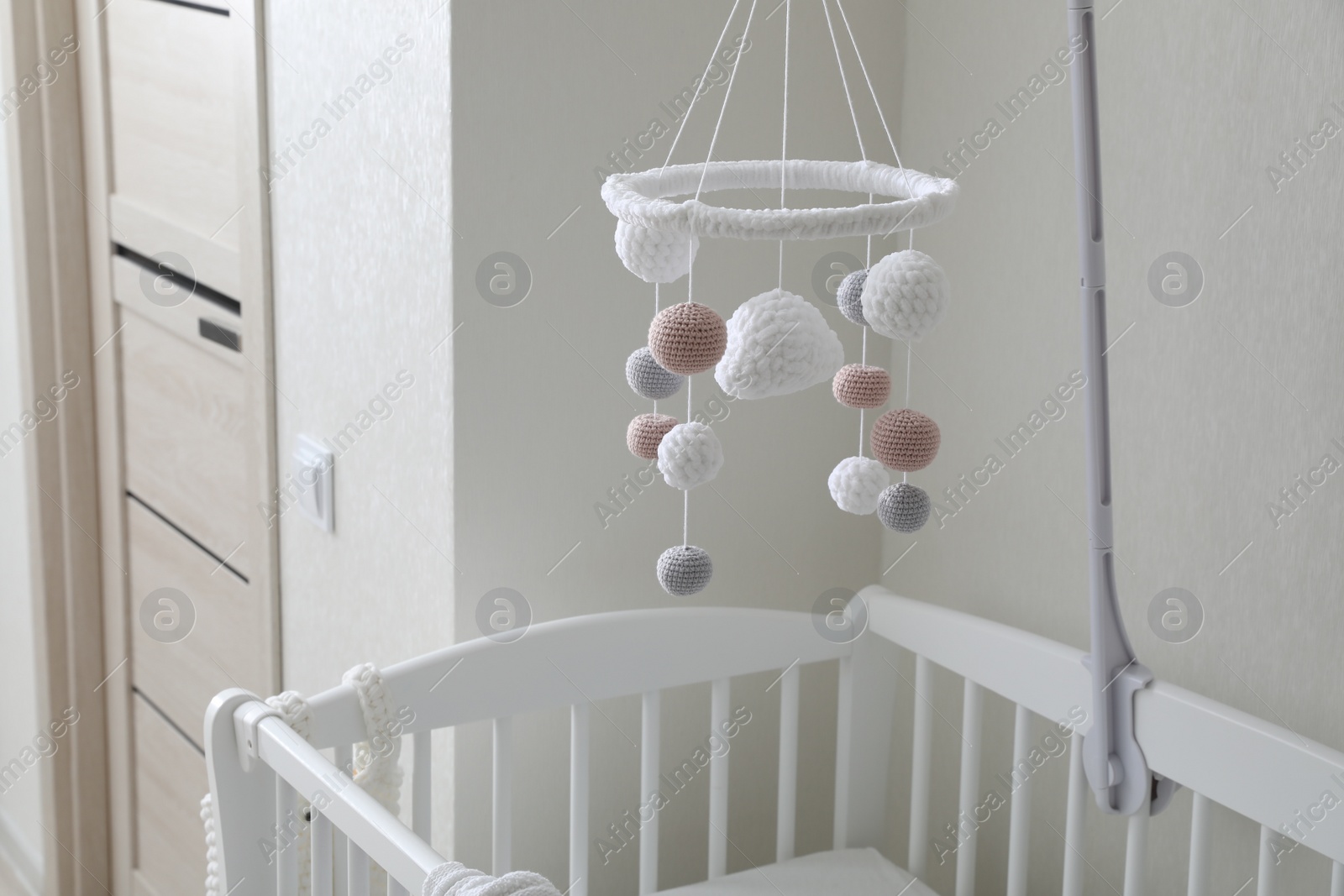 Photo of Modern crib with baby mobile in children's room. Interior design