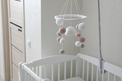 Modern crib with baby mobile in children's room. Interior design