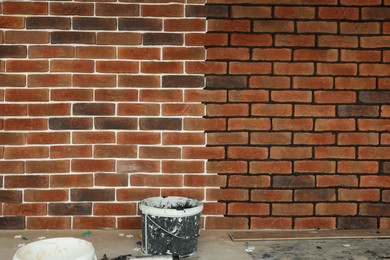 Bucket near wall with decorative bricks indoors. Tiles installation process