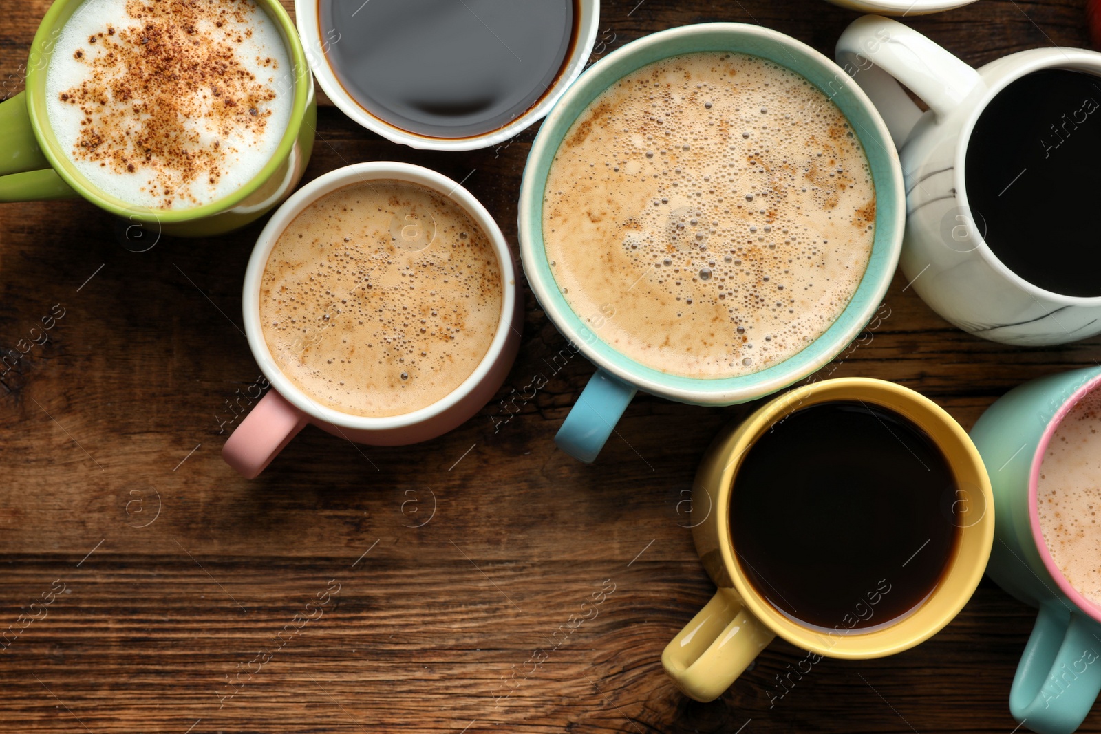 Photo of Many cups of different coffees on wooden table, flat lay