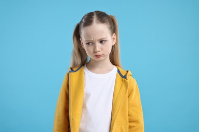 Portrait of sad girl on light blue background