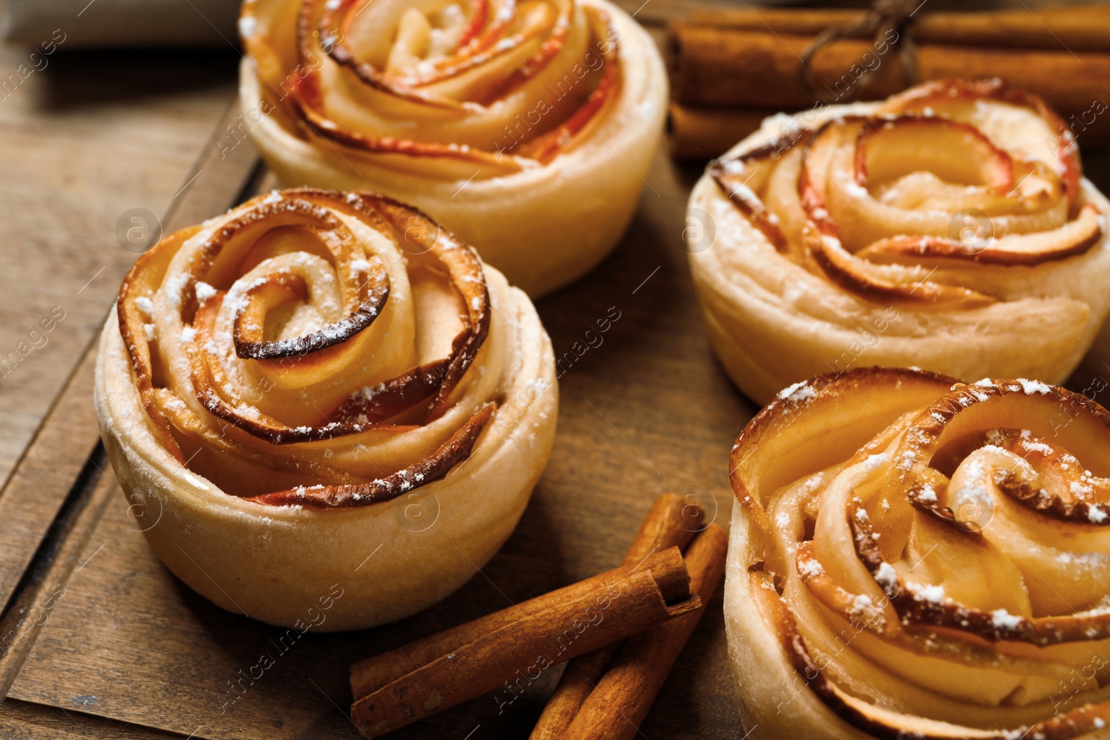 Photo of Freshly baked apple roses on wooden table, closeup. Beautiful dessert