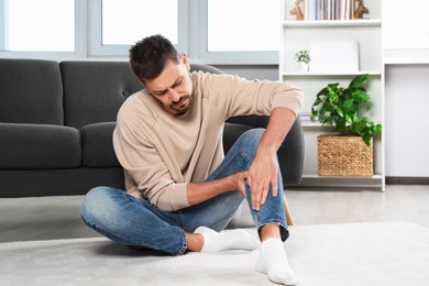Photo of Man suffering from leg pain at home