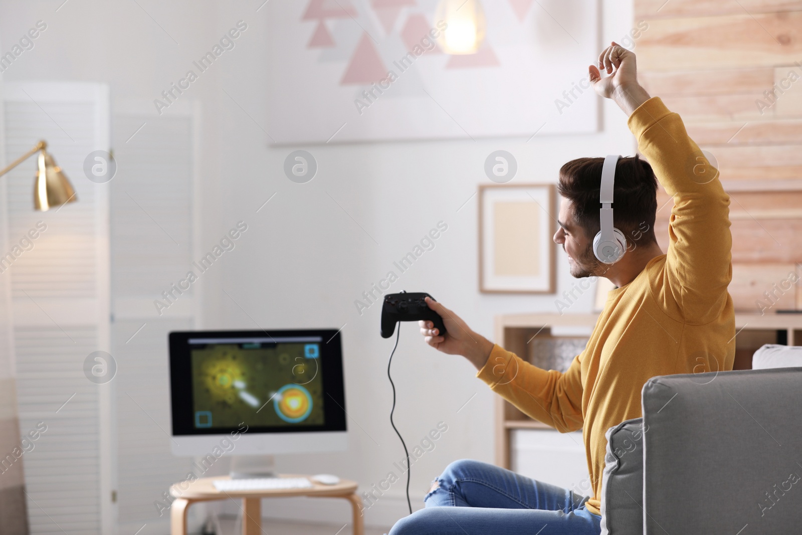 Photo of Young man playing video games at home