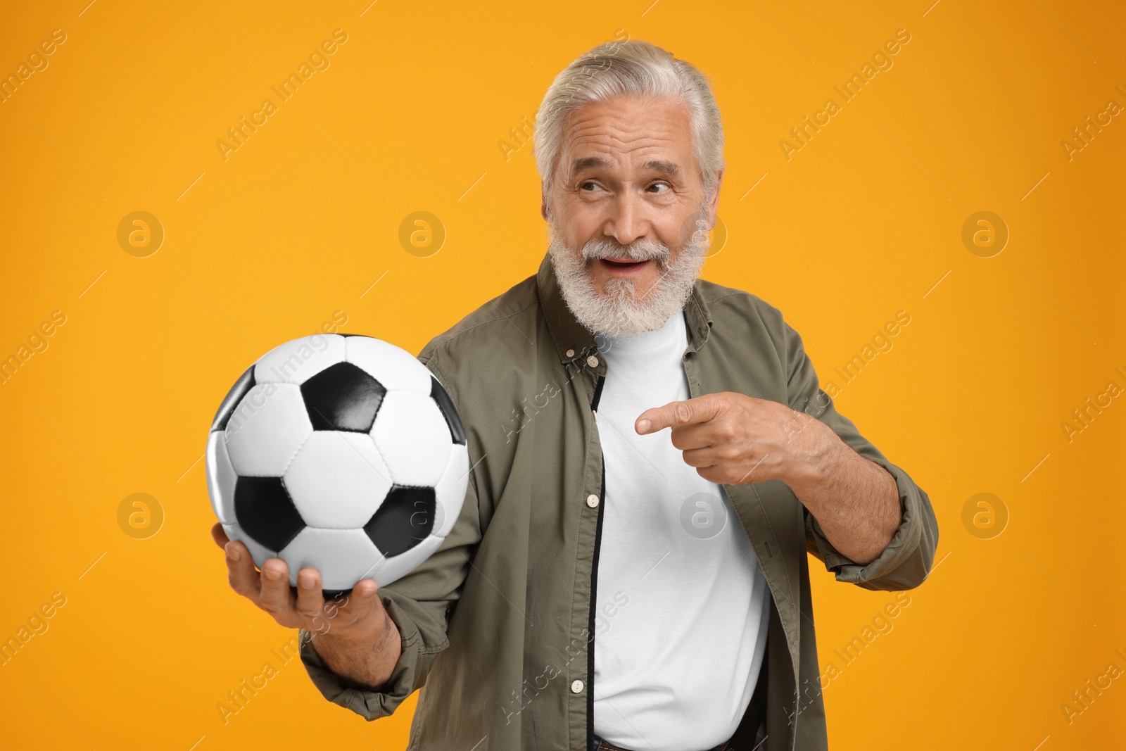 Photo of Senior sports fan with soccer ball on yellow background