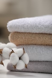 Photo of Terry towels and cotton branch with fluffy flowers on white table, closeup