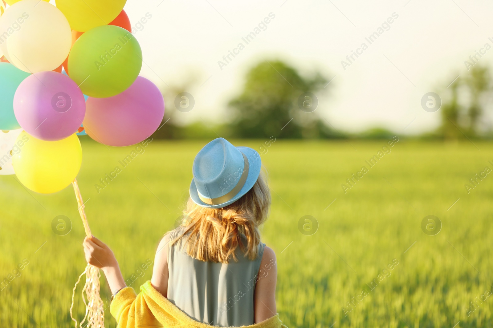 Photo of Young woman with colorful balloons in field on sunny day