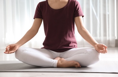 Photo of Woman practicing yoga on floor indoors, closeup