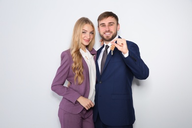 Photo of Happy young business people with house key on light background