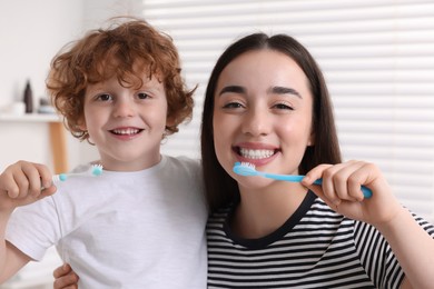 Mother and her son brushing teeth together in bathroom